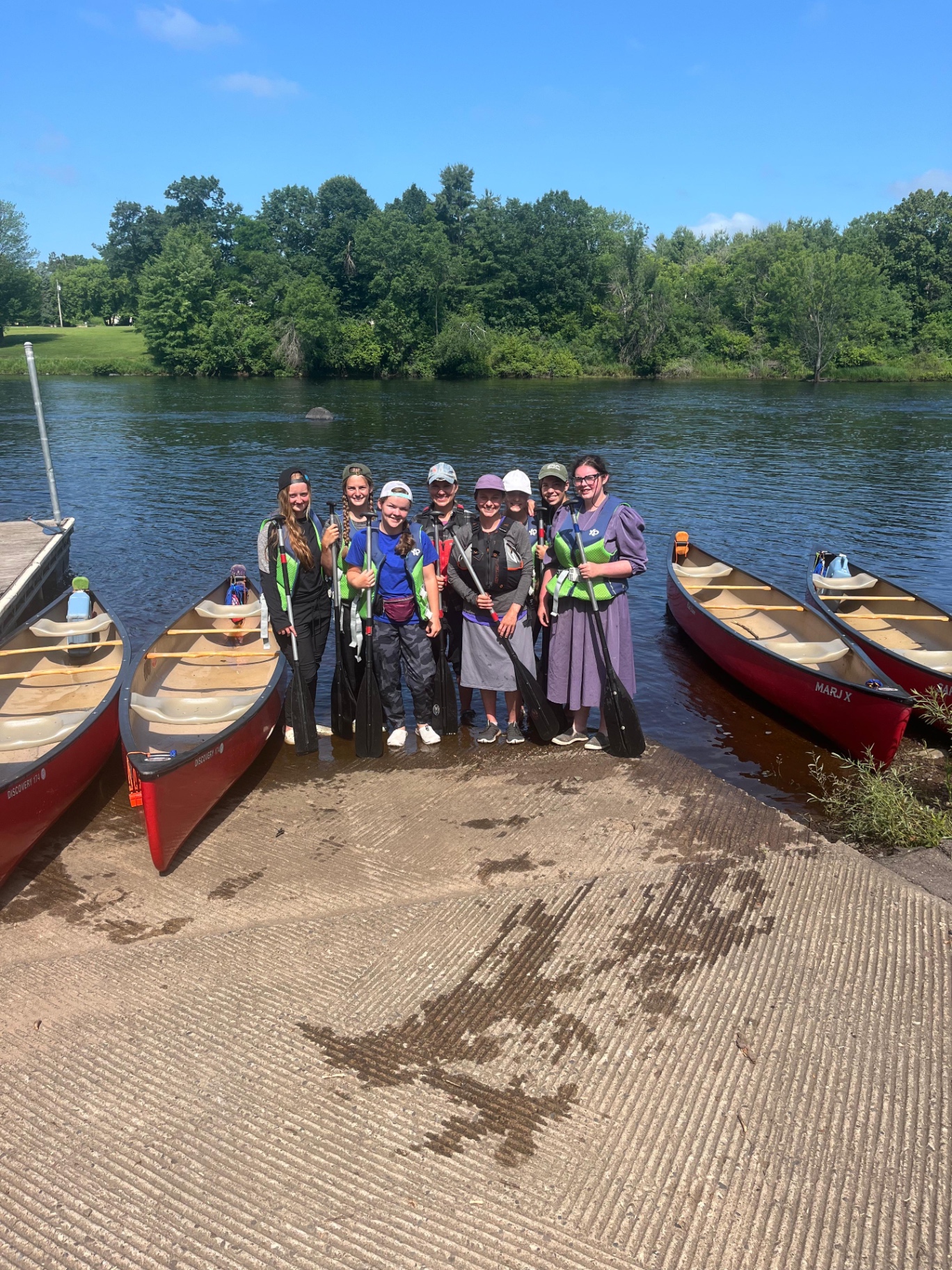 A group of young women with paddles at the river's edge before launch